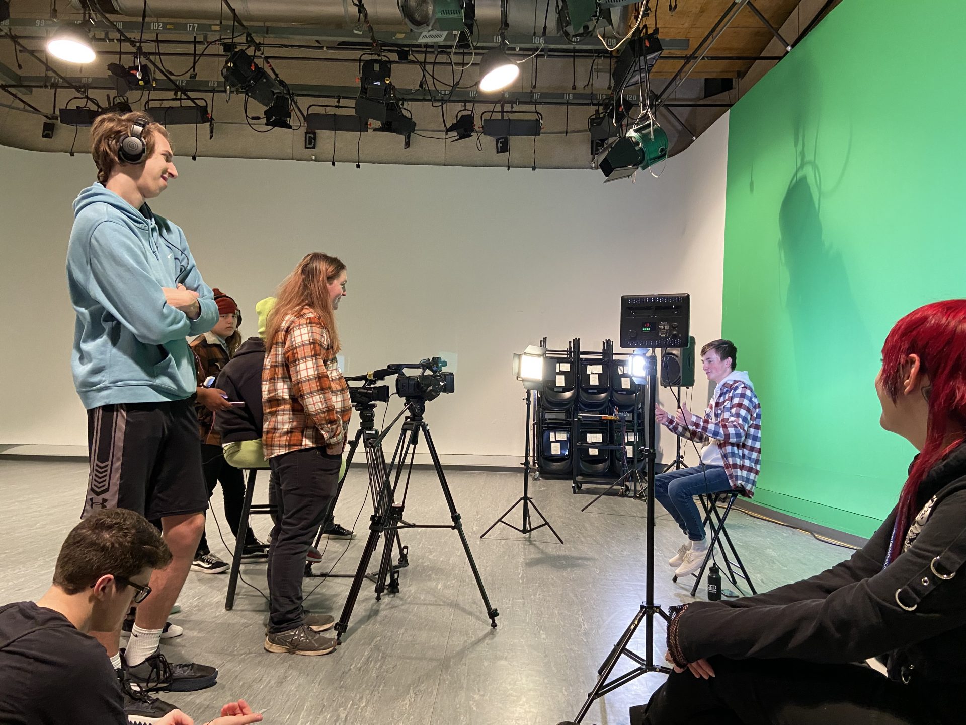 Student filming in front of a green screen