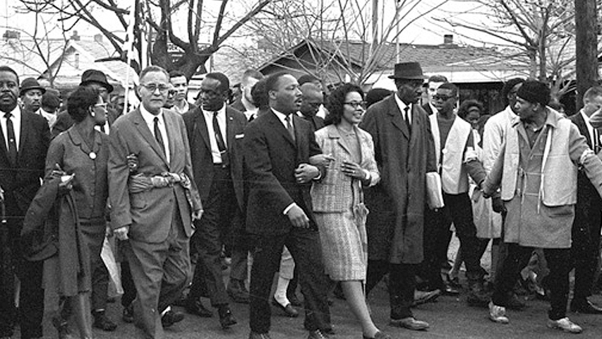 Martin Luther King Junior walking with a crowd of people